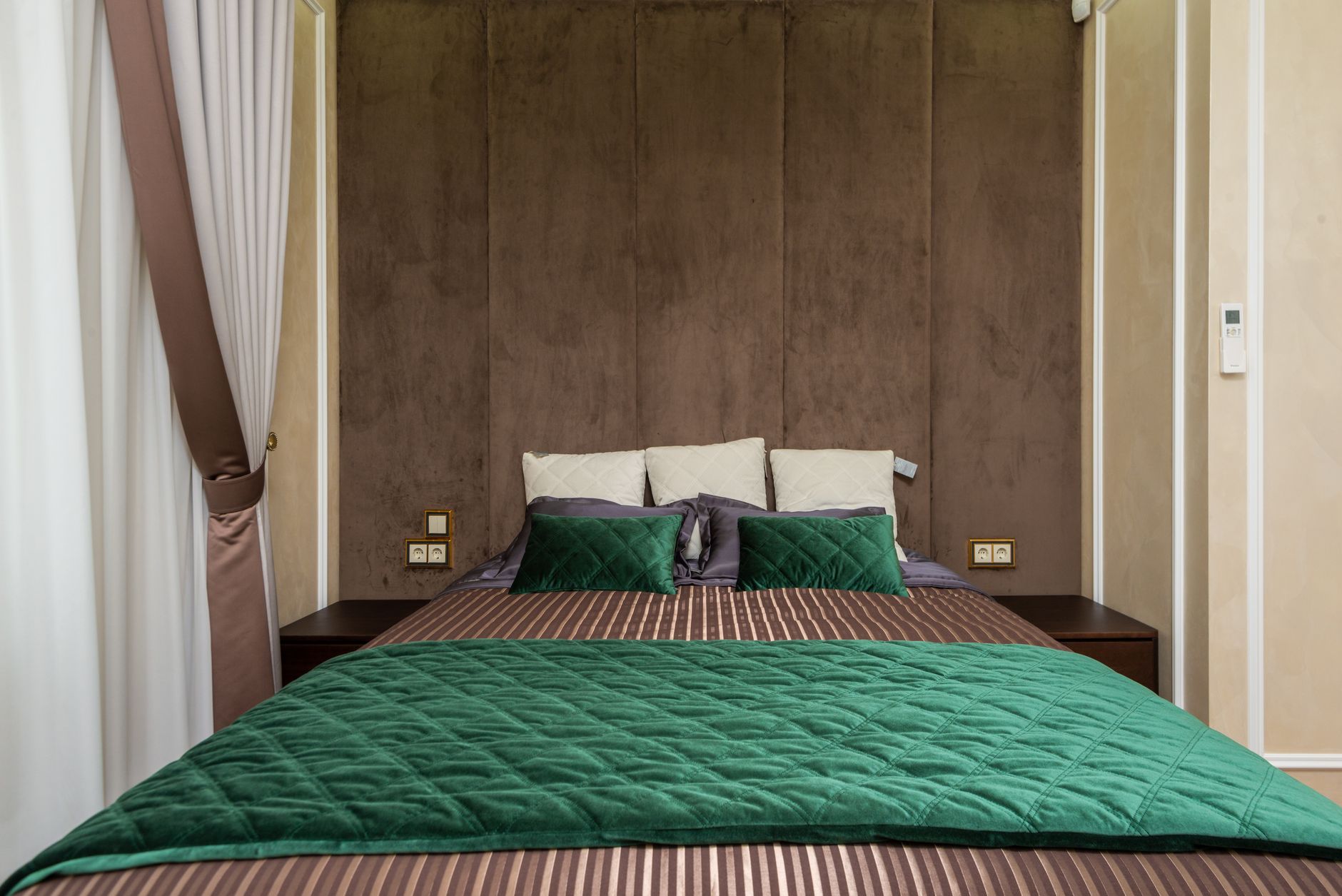 Cozy modern bedroom with green bedding and soft lighting.