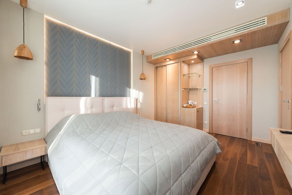 Interior of a warmly lit bedroom with a backlit headboard next to a closet