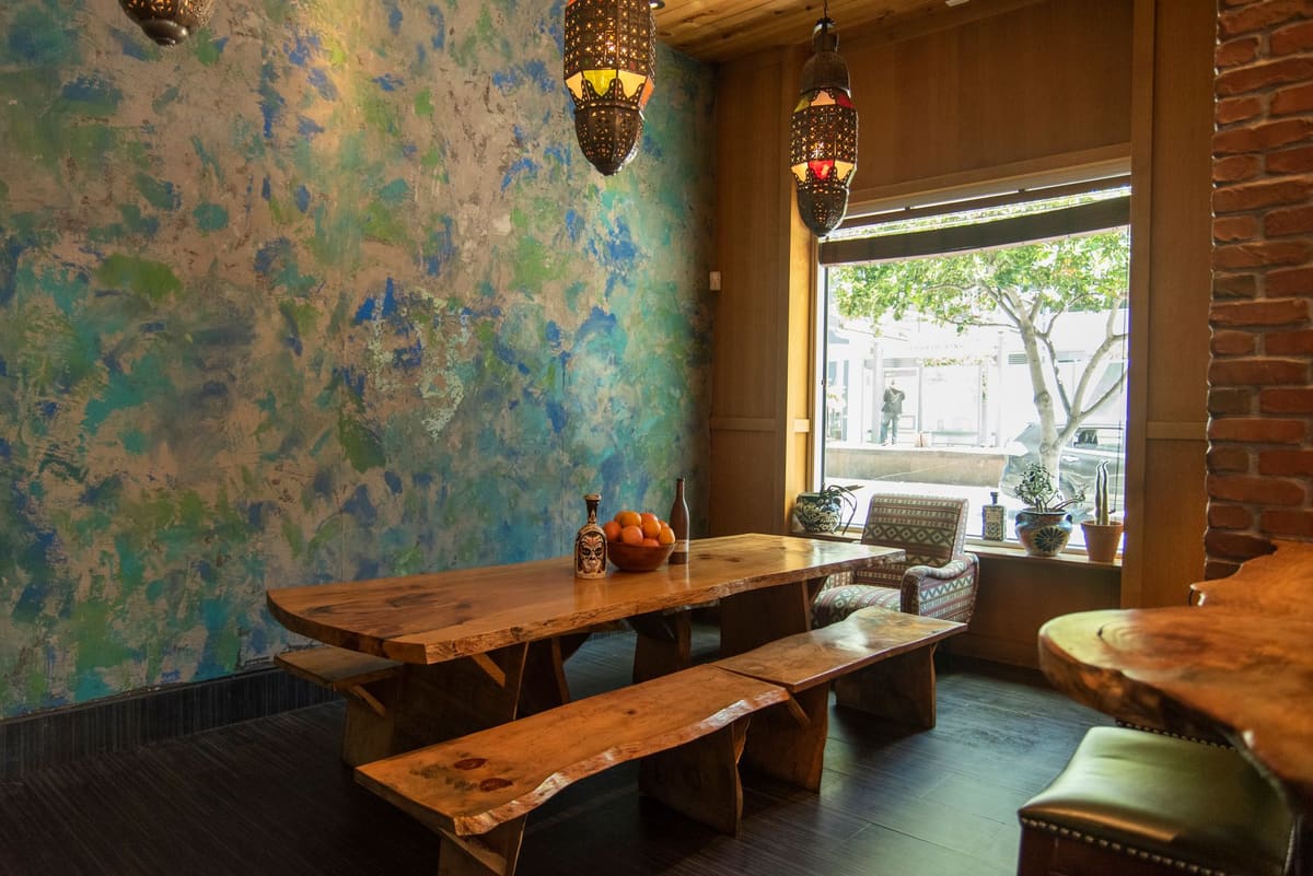 Warm and inviting rustic dining room with wooden table, artistic wall, and natural light in San Francisco.