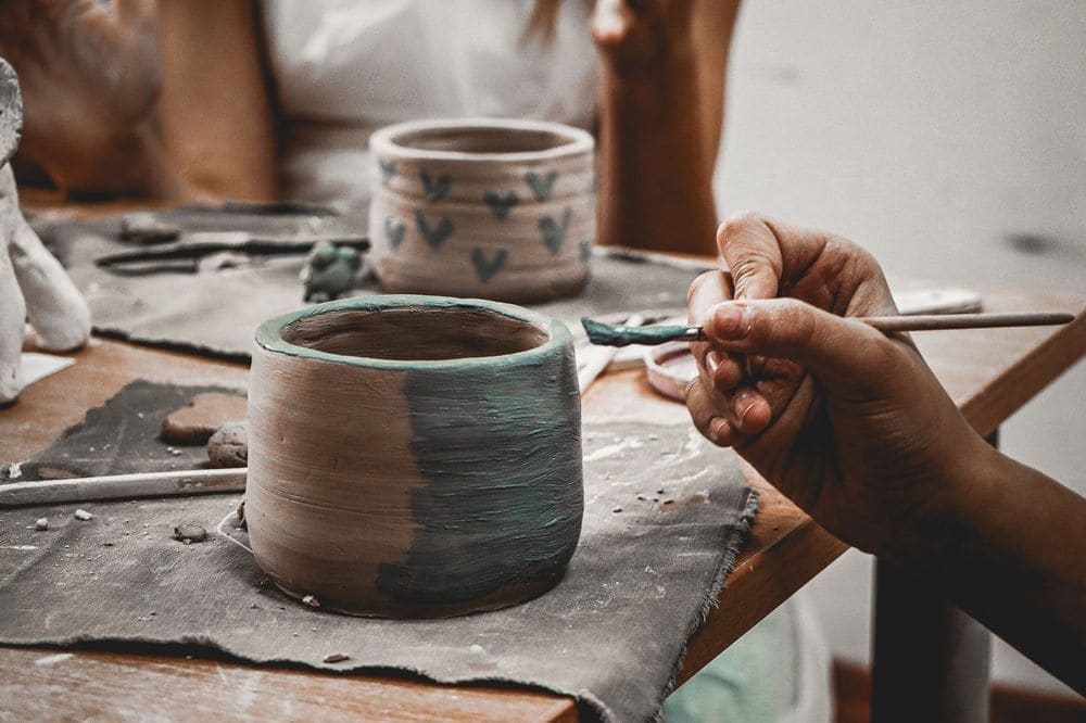 Close-up of hands skillfully painting pottery, capturing creativity and craftsmanship at work.