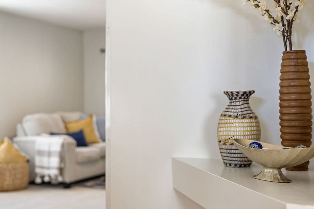 Stylish home interior featuring decorative vases on a shelf with a cozy couch in the background.