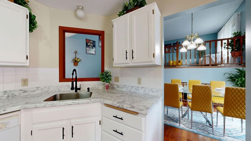 Bright modern kitchen with marble countertops overlooking a stylish dining area.