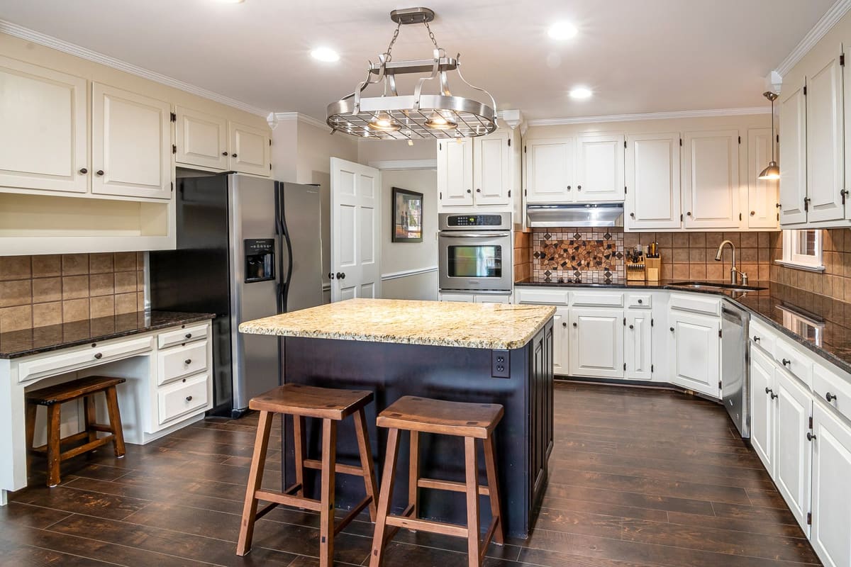 Chic kitchen design featuring granite island, hardwood floors, and stainless steel appliances.