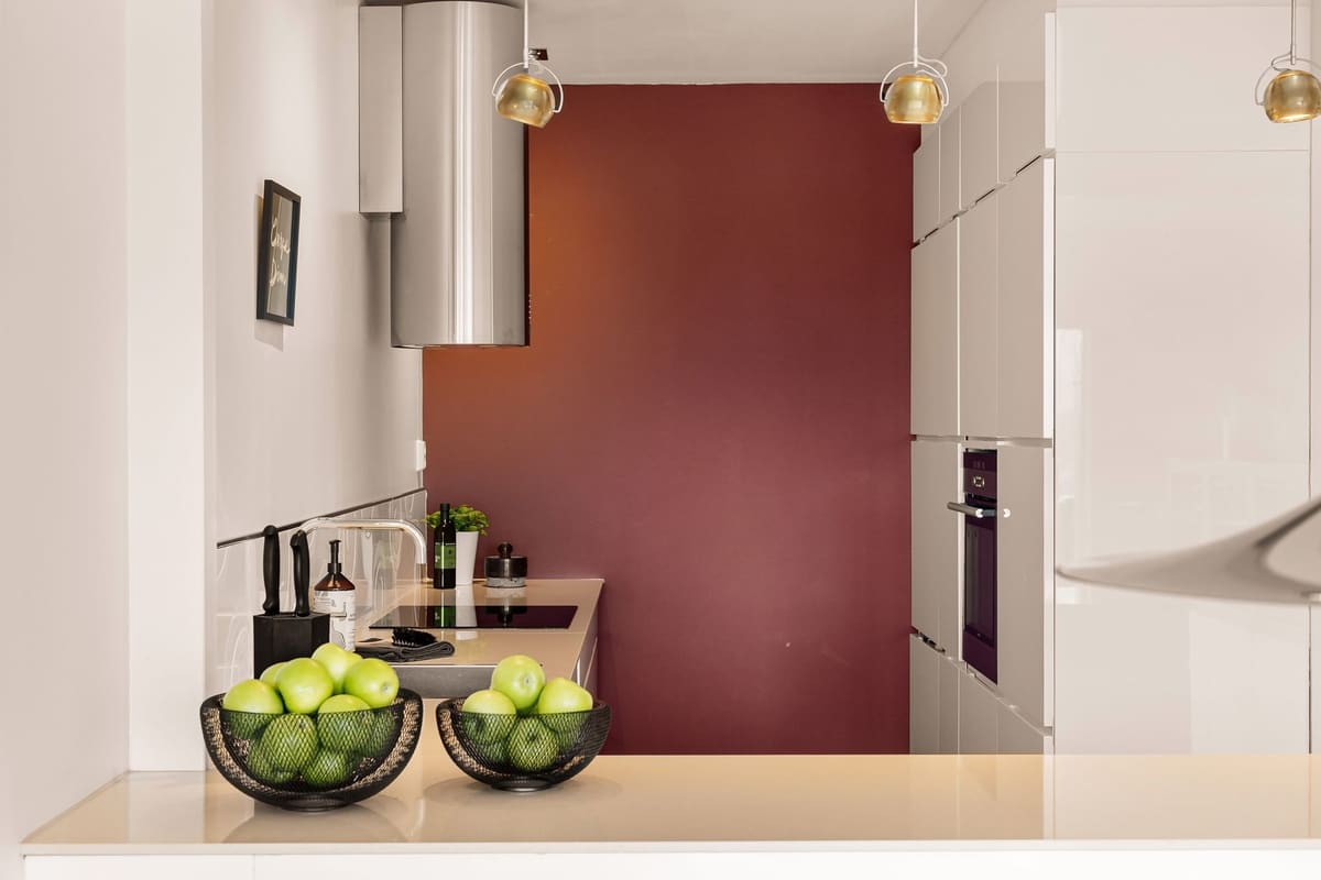 A sleek, modern kitchen interior featuring green apples in baskets, elegant cabinetry, and luxury appliances.
