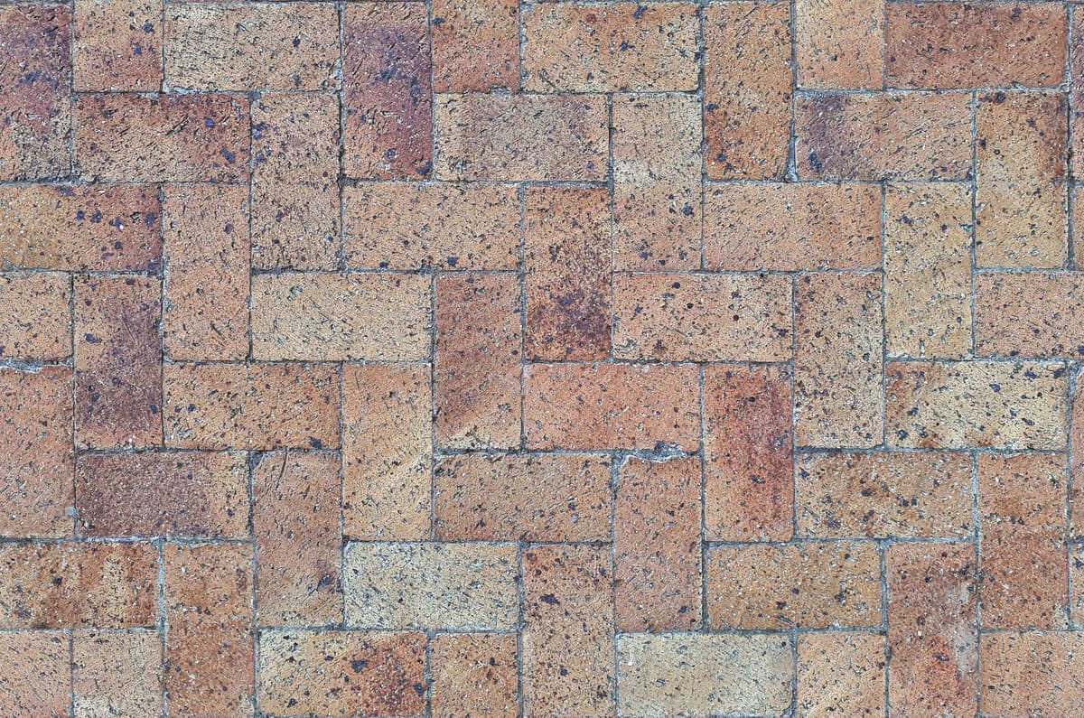 Close-up of textured brick paver pattern in a herringbone layout.