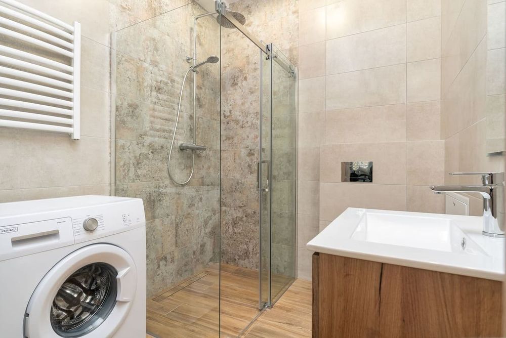 Sleek bathroom with a glass shower enclosure, a washing machine, and a contemporary sink.