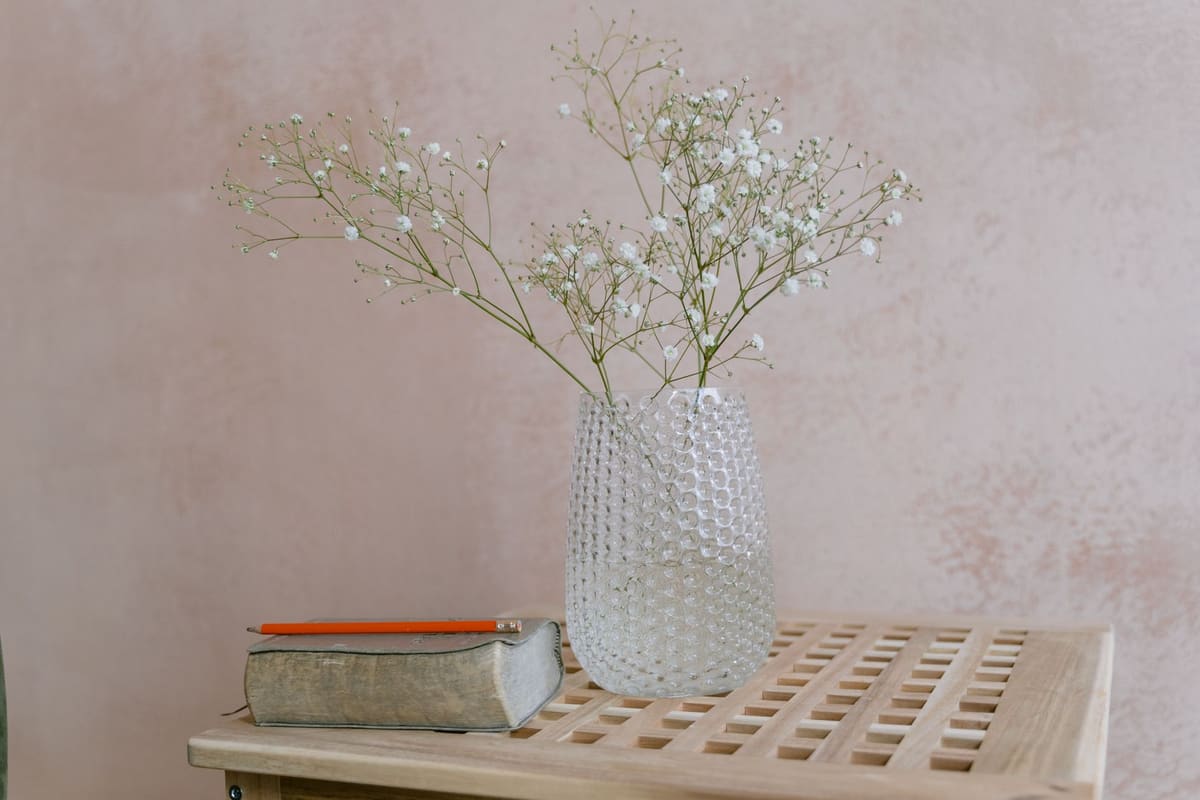 Stylish glass vase with gypsophila on a wooden table, perfect for minimal home decor inspiration.