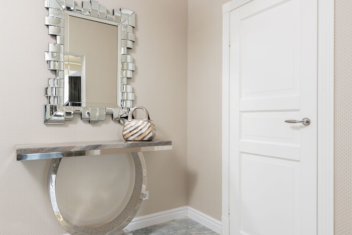 Creative design of hall with handbag on table under mirror in decorative frame against door at home