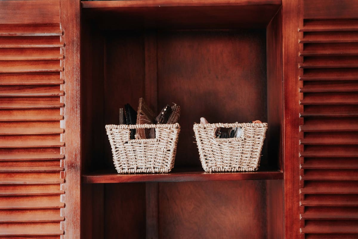 Two woven baskets on a wooden shelf within a cabinet, providing storage decor.