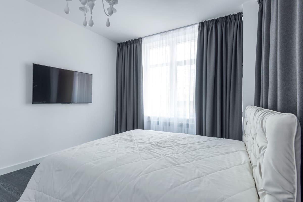 A modern bedroom featuring minimalist decor with elegant curtains.