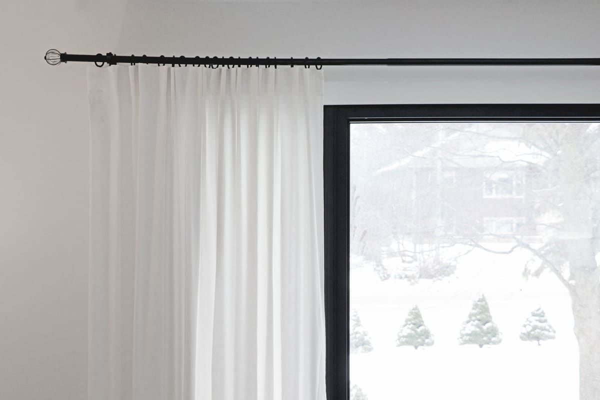 White curtains partially covering a window with a snowy outdoor view.